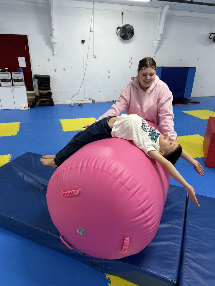 A gymnast working over the barrel with a coach